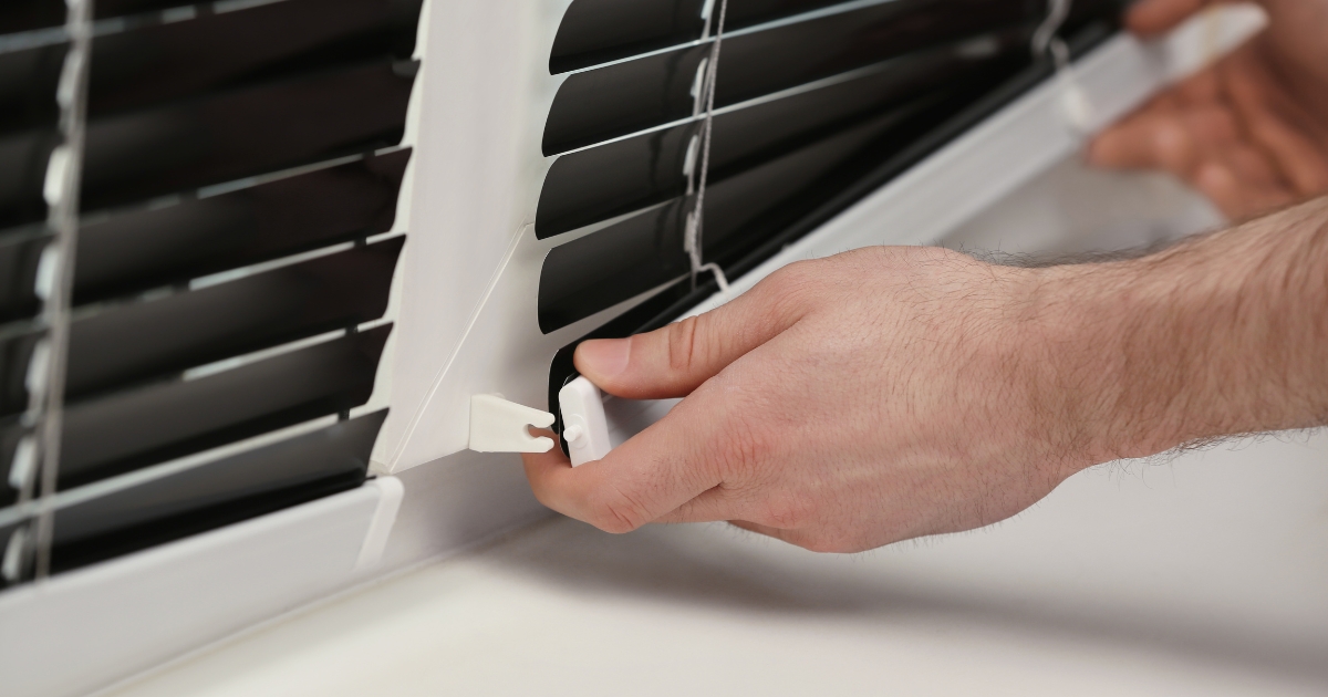 a hand fixing the venetian blinds